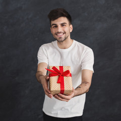 Man holding gift in his hands on gray background