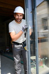 handsome young man installing bay window in new house construction site