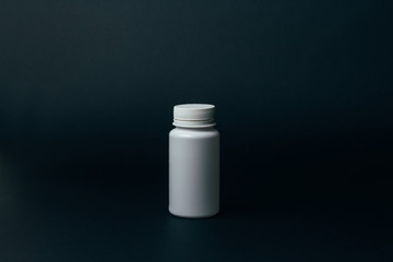 one white pill bottle on black background.vitamins.