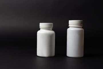 two white pill bottles on black background. horizontal