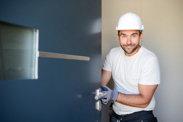 handsome young man installing a door in a new house construction site
