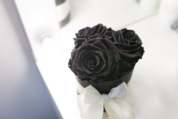 Black roses in a box with a white bow on a black background