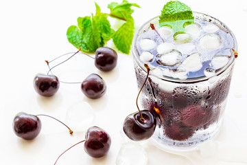 Cold refreshing detox water with cherry, mint and ice cube in glass.  Concept healthy food, diet and fitness. White background.