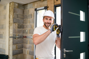 handsome young man installing a door in a new house construction site