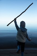 the boy runs to the water with a stick