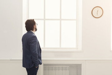 Businessman looking at clock in office. back view