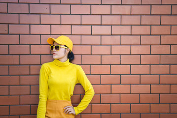 Portrait asian hipster girl on brick wall background,she wear yellow tone full body,Lifestyle of thailand people