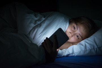 Asian woman play smartphone in the bed at night,Thailand people