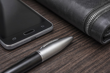 phone with a pen and purse on a wooden background