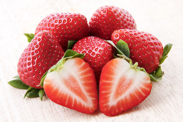 Close up of one cut strawberry on a pile of fresh ripe strawberries