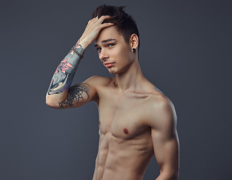 Handsome shirtless tattoed guy with stylish hair posing in a studio.