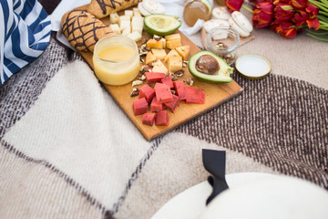 Food on a picnic is on a plaid. Avocado croissant and cheese with honey closeup