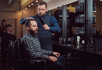 Fototapeta premium Professional barber working with a client in a hairdressing salon.