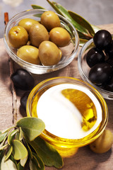 Bottle virgin olive oil and oil in a bowl with some olives