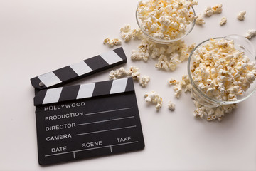 Clapperboard and popcorn on white background