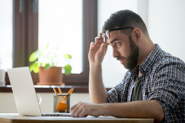 Shocked frustrated male staring at laptop screen, upset with bad online news, company business...