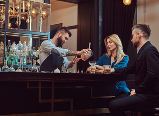 Stylish brutal barman serves an attractive couple who spend an evening on a date.