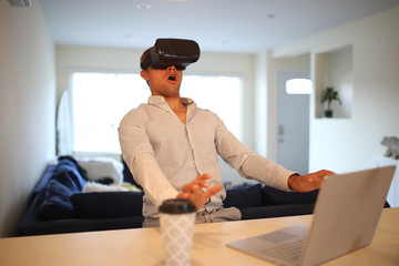 Young professional working at home, wearing virtual reality glasses. Spending a day in a VR world