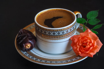 Black coffee and dates on the black table. Sweet food for Ramadan. 