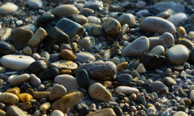 pebble stones on the sea beach, the rolling waves of the sea with foam