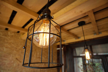 Fototapeta na wymiar Edison lamps in a metal lampshade, on the open veranda.