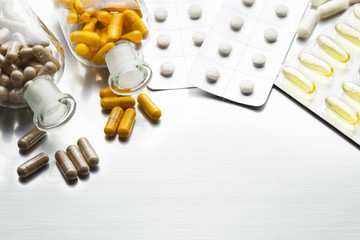 Medications as various capsules and tablets on a metal background