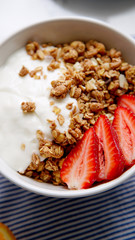 Perfect breakfast: crunchy granola with yoghurt and strawberries with a cup of black coffee on marble table