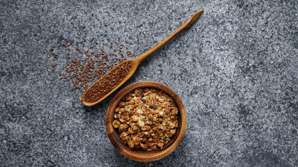 Healthy sweets cooking ingredients: granola, sesame and flax seeds, cocoa in separate bowls on gray background. Flatlay with copy space