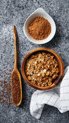 Flatlay with healthy sweets cooking ingredients: granola, sesame and flax seeds, cocoa in separate bowls on gray background