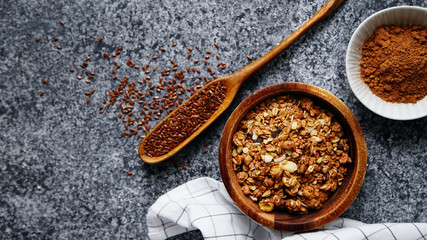 Healthy sweets cooking ingredients: granola, sesame and flax seeds, cocoa in separate bowls on gray background. Flatlay with copy space