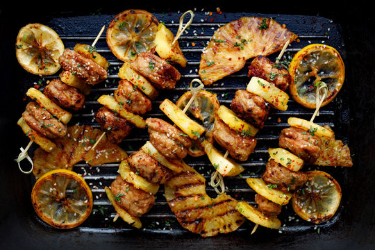 Grilled Skewers With Chicken Meatballs And Pineapple With Herbs On A Grill Plate. Fruit And Meat Skewers