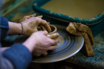 Creating jar or vase of clay close-up. Master crock. Man hands making clay jug macro. sculptor in workshop jug out of earthenware closeup. Twisted potter's wheel