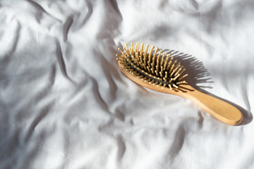 Hair fall, Hair loss problem. Wooden brown comb with hair loss on white bed cover.