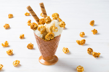 Ice cream with caramel and popcorn on a white table.