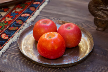 Three red apples are in a copper container