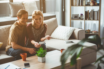Portrait of happy married couple is looking at ultrasound photo of their unborn baby. They are embracing and smiling. Pregnancy concept 