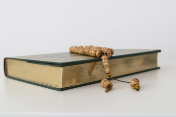 Koran and wooden rosary on the white background for Islamic concept. Holy book Quran for Muslims for Ramadan and three months.