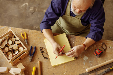top view photo of carpenter in old age holding little cross section of wooden in the hand