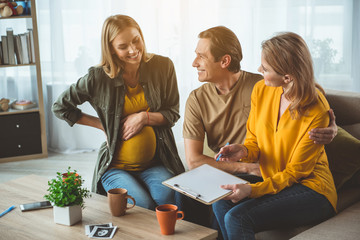 Lets sign surrogacy document. Joyful future parents are embracing and smiling. Pregnant woman is...