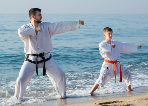 Man and teenager perform exercises on karate