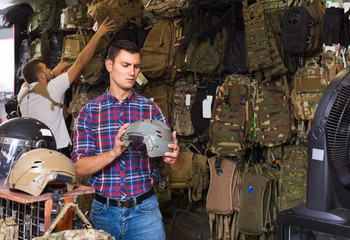 Young guys choosing helmet in military shop