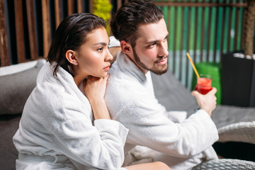 close up side view shot of young couple wdrinking a sprightly drink while resing