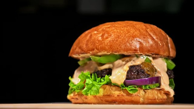 Cool beautiful fresh juicy cooked burger rotate on turntable. Very luscious air bun and marbled beef. Restaurant where each burgers is cooked by hand. Not made ideal. Not conveyor. Looks real, loving