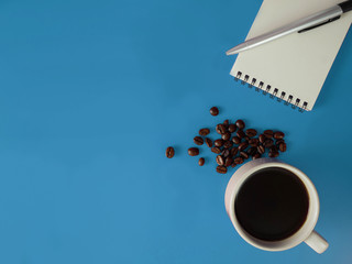 Top view,flat lay a cup of coffee with notebook and cellphone  on blue table and copy space