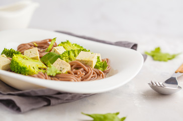 Vegetarian Soba Noodles with tofu and broccoli, white background. Healthy vegan food concept.