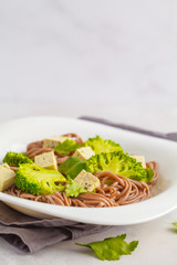 Vegetarian Soba Noodles with tofu and broccoli, white background. Healthy vegan food concept.
