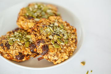 Vegan oatmeal cookies with dates and pumpkin seeds in white plate, macro. Healthy vegan food concept.