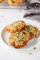 Vegan oatmeal cookies with dates and pumpkin seeds in white plate. Healthy vegan food concept.