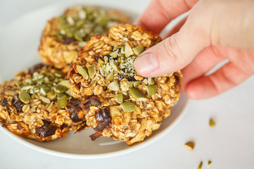 Vegan oatmeal cookies with dates and pumpkin seeds in hand. Healthy vegan food concept.