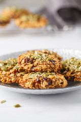 Vegan oatmeal cookies with dates and pumpkin seeds in silver plate, copy space. Healthy vegan food concept.